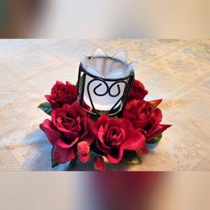 A candle holder centerpiece with red flowers